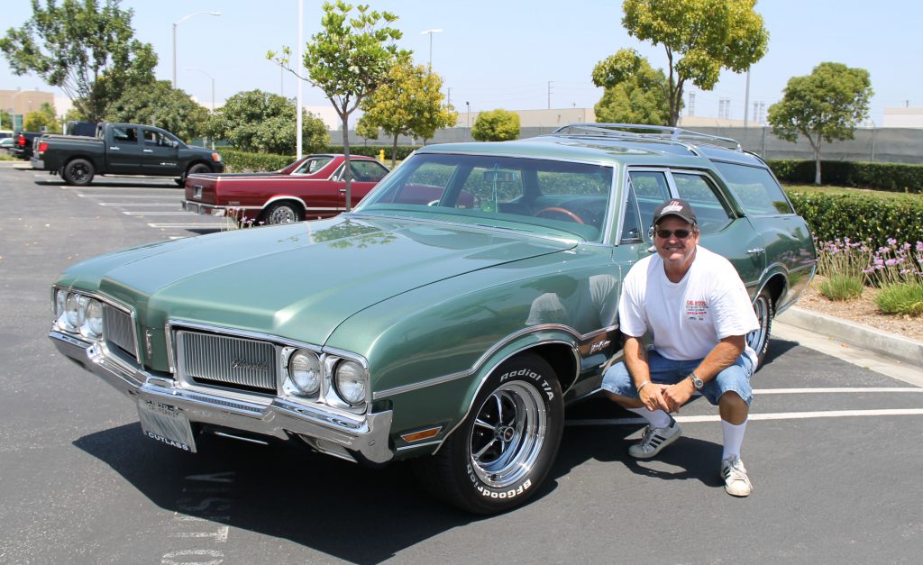 Oldsmobile wagon with man kneeling